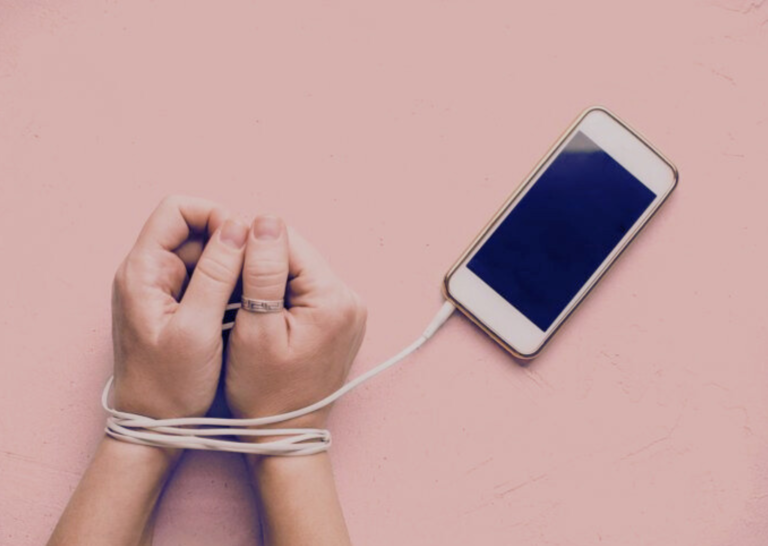 Hands tied with phone charger cable symbolizing smartphone addiction.