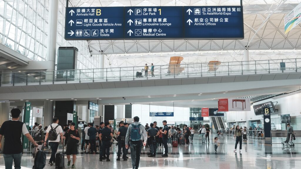 The Power of 4: A Flight Through Indian Aviation "The Power of 4: A Flight Through Indian Aviation. The image captures a bustling airport terminal filled with travelers and directional signage in both English and Chinese. Signs guide passengers to essential locations such as the Arrivals Hall, Car Park, Limousine Lounge, Medical Centre, and Airline Offices. Security personnel are present, ensuring smooth operations. The terminal's modern design features large windows and high ceilings, emphasizing efficiency and global connectivity in Indian aviation." Let me know if you'd like any refinements!