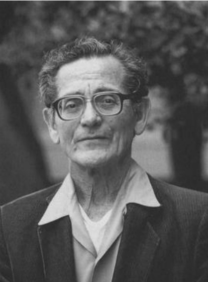 brain3 "The Brain Goes - 1-2-Cha-Cha-Cha: Black-and-white photograph showing an elderly individual dressed formally in a suit jacket and shirt, standing outdoors, with trees forming a serene backdrop."